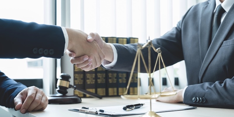 Handshake after Lawyer providing legal consult business dispute service to the man at the office with justice scale and gavel hammer